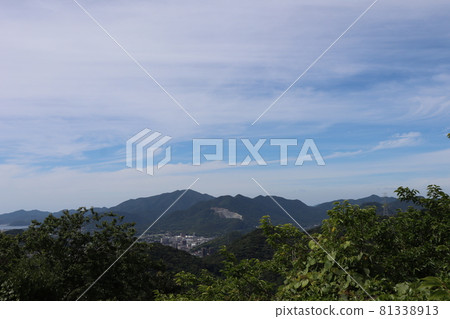 A city with thin clouds, blue sky, green trees seen from a hill, buildings in mountains and valleys, a quarry, and a seascape that can be seen a little in the distance A city with thin clouds, blue sky, green trees seen from a hill, buildings in mountains and valleys, a quarry, and a seascape that can be seen a little in the distance 81338913