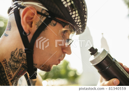 Close-up of young man, sportive cyclist drinking water. Healthcare concept Close-up of young man, sportive cyclist drinking water. Healthcare concept 81340559