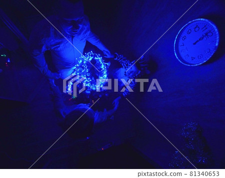 The family fast and fanny decorates the Christmas tree. Top view. Time on the clock is 23.45 on wall. Happy dad, mom, daughter are run around tree. 81340653