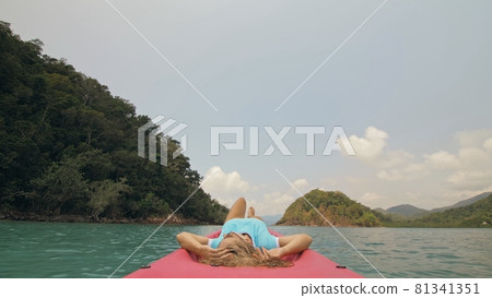 Seductive woman lifts up long legs lying on canoe on sea Seductive woman lifts up long legs lying on canoe on sea 81341351