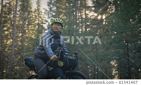 The woman travel on mixed terrain cycle touring with bike bikepacking. The traveler journey with bicycle bags. Magic forest park. The woman travel on mixed terrain cycle touring with bike bikepacking. The traveler journey with bicycle bags. Magic forest park. 81341407