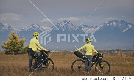 The man and woman travel on mixed terrain cycle touring with bikepacking. The love couple journey with tent in with bicycle bags. Stylish sportswear. The man and woman travel on mixed terrain cycle touring with bikepacking. The love couple journey with tent in with bicycle bags. Stylish sportswear. 81342109