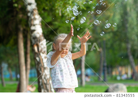 Little cute girl in the summer park blowing bubbles and having fun Little cute girl in the summer park blowing bubbles and having fun 81343555