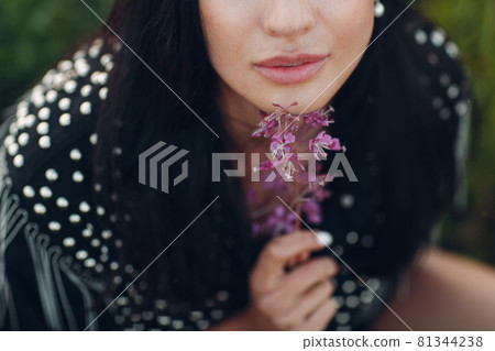 Young brunette woman on blooming Sally flower field. Lilac flowers and girl. 81344238