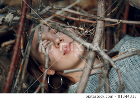 Pretty young woman outdoor in the park under dry tree branches Pretty young woman outdoor in the park under dry tree branches 81344315
