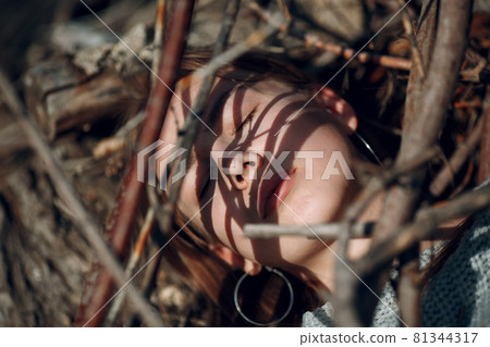 Pretty young woman outdoor in the park under dry tree branches Pretty young woman outdoor in the park under dry tree branches 81344317