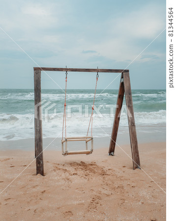 Wooden swing on the shores of the raging sea. Wooden swing on the shores of the raging sea. 81344564