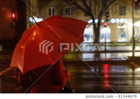 Rainy evening. A woman silhouette with umbrella and running traffic with drops of rain. Autumn time. 81344679