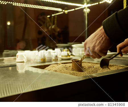 Close up hands of a man cooking turkish coffee on hot golden sand. Close up hands of a man cooking turkish coffee on hot golden sand. 81345908