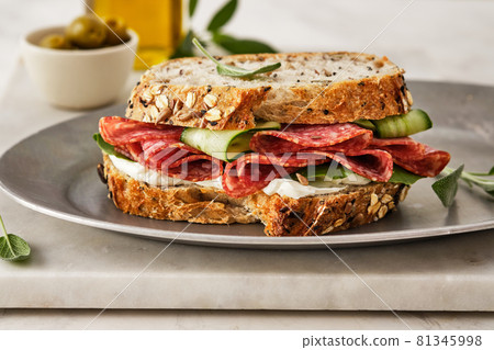 Sandwich with salami sausage and cucumber on marble background. Sandwich with salami sausage and cucumber on marble background. 81345998