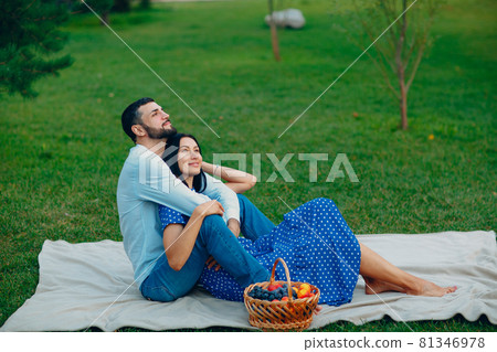 Young adult woman and man couple picnic at green grass meadow in park. Young adult woman and man couple picnic at green grass meadow in park. 81346978
