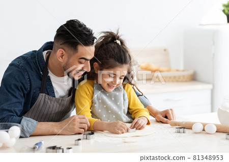 Cute little arab girl cutting different cookie shapes from dough with dad Cute little arab girl cutting different cookie shapes from dough with dad 81348953