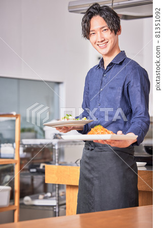 Image of a young man in an apron carrying food Image of a young man in an apron carrying food 81351092