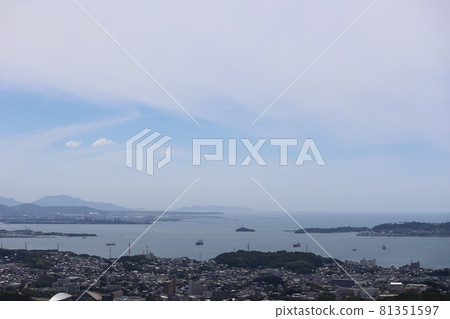 A landscape with the sea, small islands, big towns, factory areas, hazy mountains, thin clouds and blue sky seen from a hill A landscape with the sea, small islands, big towns, factory areas, hazy mountains, thin clouds and blue sky seen from a hill 81351597