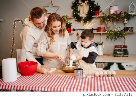 little boy pours milk himself. family together prepares dishes for the new year little boy pours milk himself. family together prepares dishes for the new year 81357112