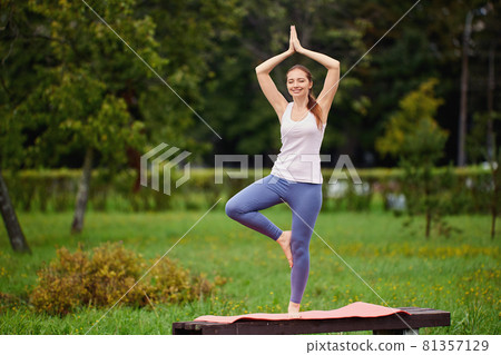 Woman makes yoga training in park using mat. Woman makes yoga training in park using mat. 81357129