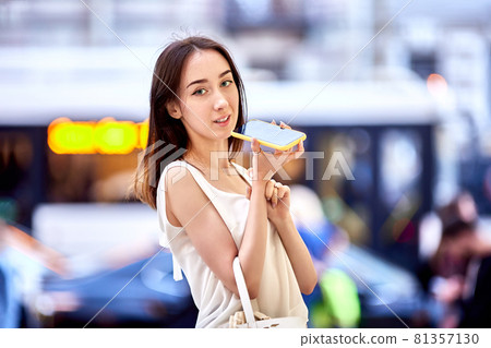 Graceful woman is using smartphone for talking outside. Graceful woman is using smartphone for talking outside. 81357130