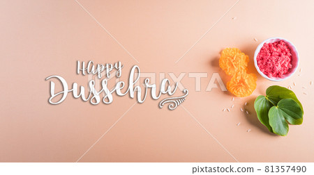 Happy Dussehra. Yellow flowers, green leaf and rice on pastel background. Dussehra Indian Festival concept. 81357490