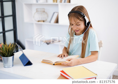 Little caucasian girl in headphones have video call distant class with teacher at home 81357576