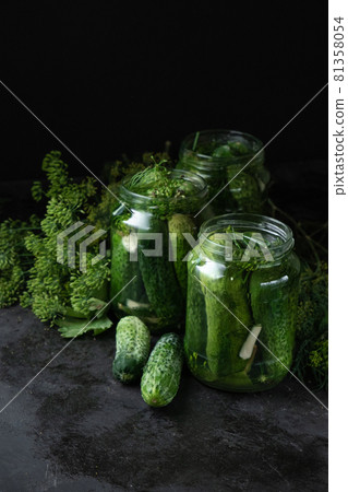 Homemade pickled cucumbers in the glass jar and fresh dill on black background. Low key photo, copy space 81358054