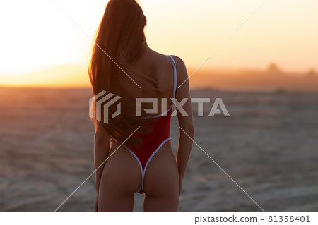 Sensual young female enjoying sunset on sandy coast Sensual young female enjoying sunset on sandy coast 81358401