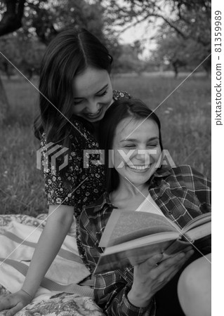 Two sisters walk in nature and communicate. They take pictures at sunset. 81359989