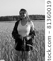Black and white vintage photography. The girl walks about a wheat field and smiles. 81360019