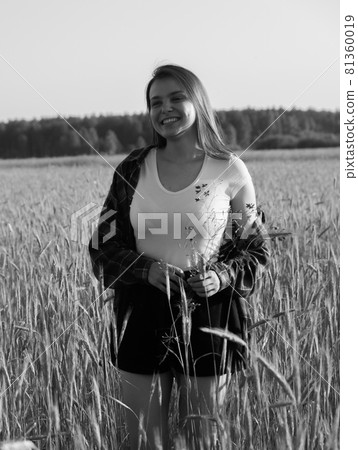 Black and white vintage photography. The girl walks about a wheat field and smiles. 81360019