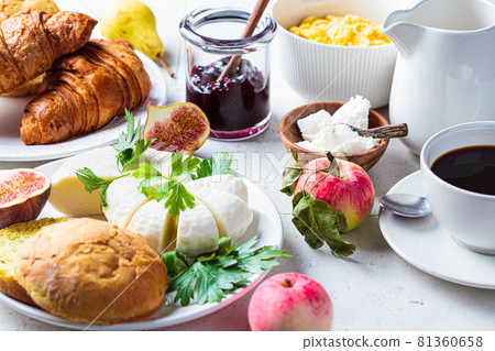 Breakfast table with cornflakes, croissants, fruit, cheese and cup of coffee. 81360658