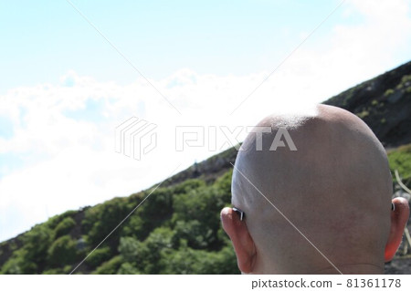 Back view of a shaved-headed man climbing a mountain 81361178