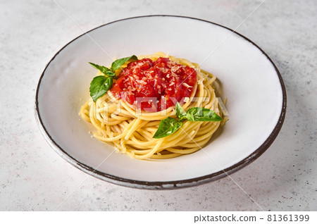 Close up spaghetti in tomato sauce, parmesan cheese and basil on white plate Close up spaghetti in tomato sauce, parmesan cheese and basil on white plate 81361399