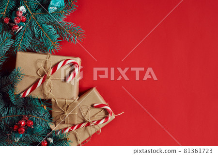 Christmas composition of pine cones, spruce branches and stack of gift boxes on red background 81361723
