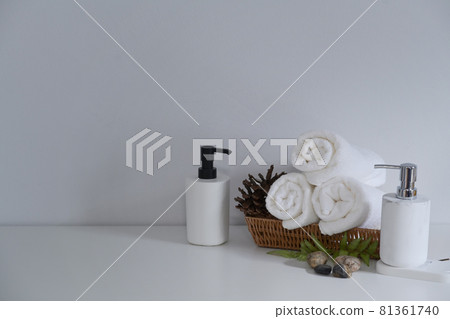 Soap bottles and wooden tray of towels on white table. Beauty spa treatment and relax concept. Soap bottles and wooden tray of towels on white table. Beauty spa treatment and relax concept. 81361740