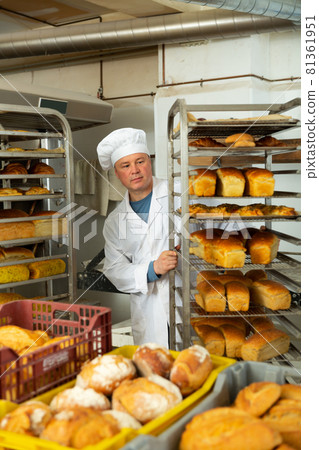 Baker putting baked bread on rack 81361951