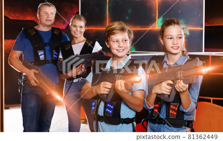 Happy teen brother and sister standing with laser pistols during 81362449
