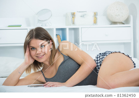 Portrait of young sexy woman lying with smartphone in bed Portrait of young sexy woman lying with smartphone in bed 81362450
