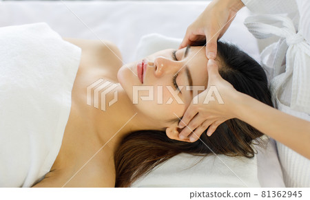 Adult beautiful asian women black long hair sleep for head massage spa service with covered wrap by white towel on her look feel relax and blurry with flowers background 81362945