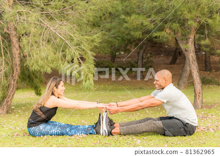Sporty couple doing exercises together while sitting and holding hands 81362965