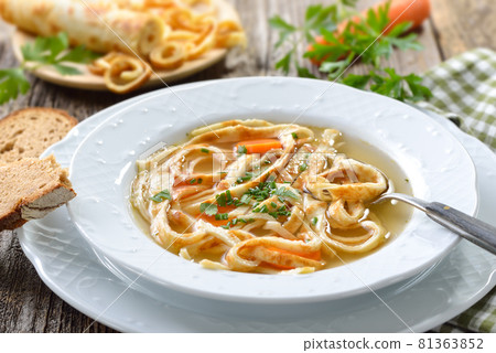 Delicious homemade beef broth with pancake strips, served with bread on a wooden table 81363852