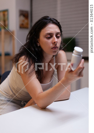 Caucasian woman with headache holding bottle of pills Caucasian woman with headache holding bottle of pills 81364015