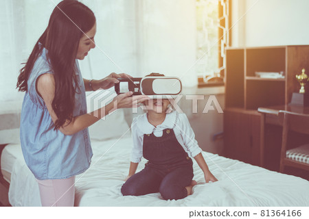Mother and little daughter having fun wear virtual reality glasses are watching new technology 81364166
