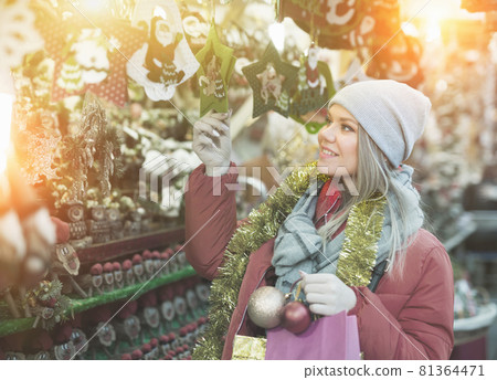 Girl choosing Christmas gifts outdoor on the street 81364471