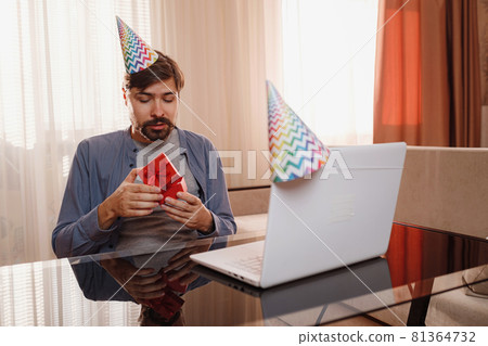 young man sitting at the table and talking by video call to friends. young man sitting at the table and talking by video call to friends. 81364732