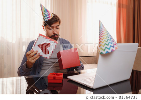 young man sitting at the table and talking by video call to friends. young man sitting at the table and talking by video call to friends. 81364733