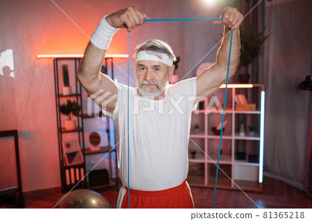 Mature man having evening workout with resistance band 81365218