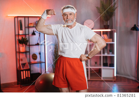 Caucasian older man showing his muscular biceps at home 81365281