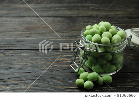 Glass jar with wasabi nuts on rustic wooden background Glass jar with wasabi nuts on rustic wooden background 81366666