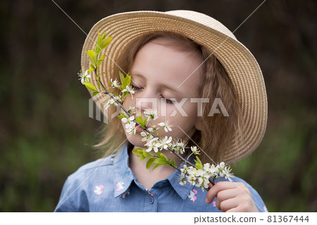 Cute little girl inhaling the aroma of cherry flowers in a park Cute little girl inhaling the aroma of cherry flowers in a park 81367444