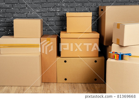Stack of cardboard boxes in the empty room against black brick wall 81369668