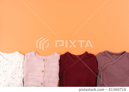 Clothes of baby girl on orange background top view Clothes of baby girl on orange background top view 81369718